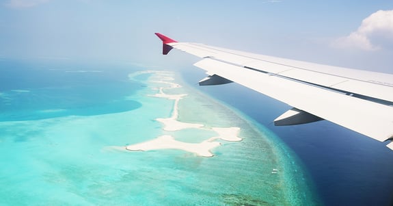 Stock image of airplane wing flying over tropical islands